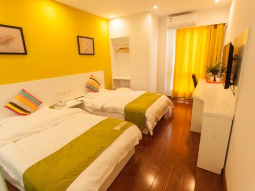 two beds in a hotel room with yellow walls at Shell Hefei Economic Development Zone Hong Kong and Macao Square Hotel in Hefei