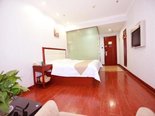 a bedroom with a bed and a wooden floor at GreenTree Inn Yinchuan Pedestrian Street Xinhua Department Store Business Hotel in Yinchuan