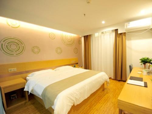 a bedroom with a large white bed and a desk at GreenTree Inn Dezhou Qingyun Government Express Hotel in Xiaozheng