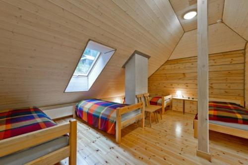a attic room with two beds and a window at Saulės Slėnis in Plateliai