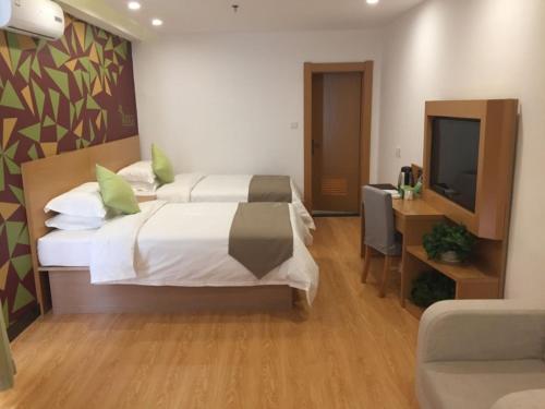 a bedroom with a bed and a desk and a television at Vatica Xingtai Qiaoxi District Yongkang Street Technical College Hotel in Xingtai