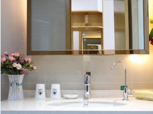 La salle de bains est pourvue d'un lavabo, d'un miroir et de fleurs. dans l'établissement GreenTree Inn Hefei Feidong New District Huishang City Express Hotel, à Feidong
