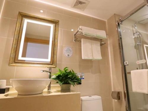 a bathroom with a sink and a mirror and a shower at GreenTree Inn Taizhou Taixing City Xuanbao Town Zhongyang Road Express Hotel in Yong'anzhou