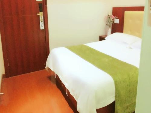 a bedroom with two beds with white sheets and a green blanket at GreenTree Inn Shanghai Outlets National Convention Centre XuLe Road Shell Hotel in Qingpu