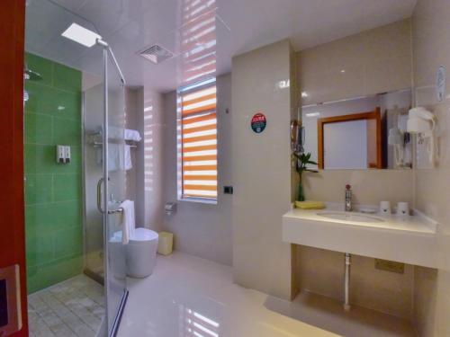 een badkamer met een douche, een wastafel en een douche bij GreenTree Inn Huanggang Qichun County Ouyada Square Express Hotel in Qichun