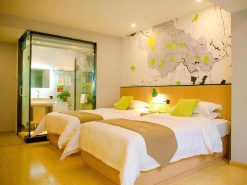 two beds in a hotel room with a map on the wall at Vatica Fuyang Linquan County Jiangziya Square Hotel in Fuyang