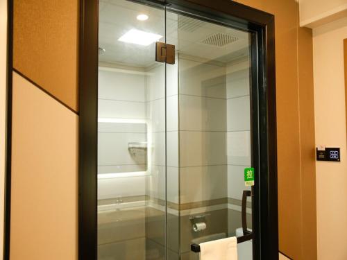 a glass shower door in a bathroom with a toilet at Shell Tianshui Maiji District Erma Road Walking Street Hotel in Tianshui