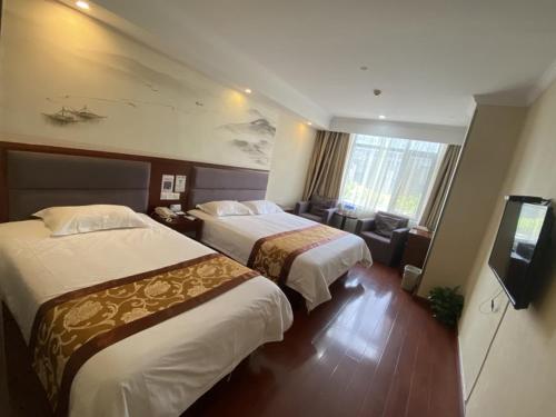 a hotel room with two beds and a flat screen tv at GreenTree ShangHai JinShan Wanda Plaza Longxiang Road Express Hotel in Jinshan