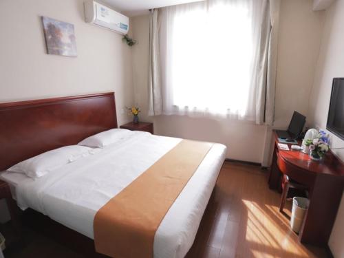 a bedroom with a large bed with a desk and a window at GreenTree Inn Hebei Baoding Sanfeng Road Agricultural University Shell Hotel in Baoding