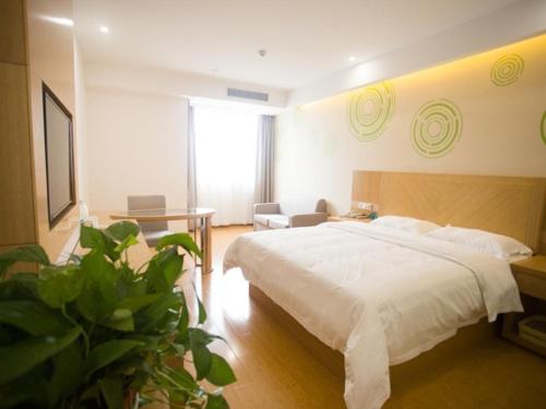 a bedroom with a bed and a table and a plant at GreenTree Inn Fuyang Linquan County Yiwu Trade City Express Hotel in Jinzhuang