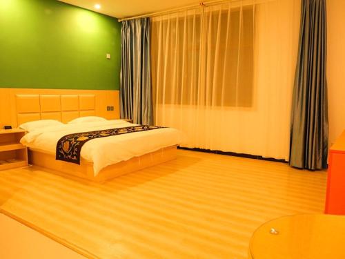 a bedroom with a bed with a green wall at Shell Baodong Xiongxian Jidong Hotel in Xiong