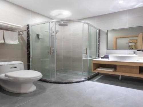 a bathroom with a shower and a toilet and a sink at Shell Ningbo Gaoqiao Subway Station Hotel in Ningbo