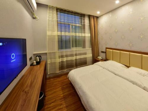 a bedroom with a bed and a flat screen tv at Shell Zhaozhong Ancient Street, Jinzhong County Railway Station Hotel in Qixian