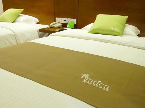 two beds in a hotel room with a kittilus sign on them at Vatica AnHui Fuyang Linquan South Jiefang Hotel. in Linquan