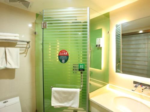 a bathroom with a glass shower and a sink at GreenTree Inn Zhangye Liangjiadun Town Zhangnin Road Hotel in Zhangye