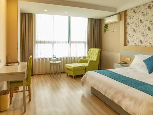 a hotel room with a bed and a desk and chair at GreenTree Inn Rugao bus station in Nantong