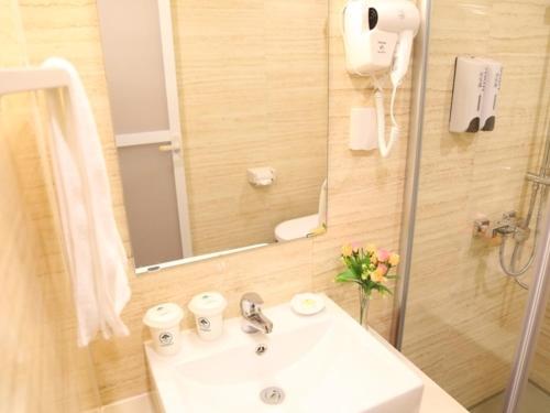 a bathroom with a sink and a shower with a mirror at GreenTree Inn JiangSu YiXing DingShu Town JieFang East Road Express Hotel in Yixing
