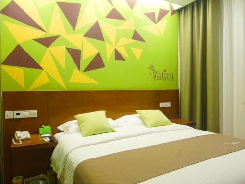 a bedroom with a large bed and a green wall at Vatica AnHui Fuyang Linquan South Jiefang Hotel. in Linquan