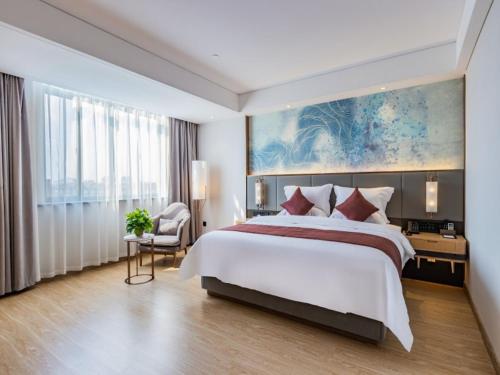 a bedroom with a large bed and a large painting at Gya Jiaxing City Haiyan County Chang'an South Road Lishi Plaza Hotel in Jiaxing