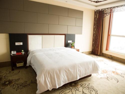 a bedroom with a large white bed and a large window at GreenTree Inn Shandong Zaozhuang Shanting JinkeGuoji Yijiaren Business Hotel in Zaozhuang