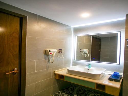 a bathroom with a sink and a mirror at GME Bozhou Qiaocheng District Jian'an Road Railway Station Hotel in Bozhou