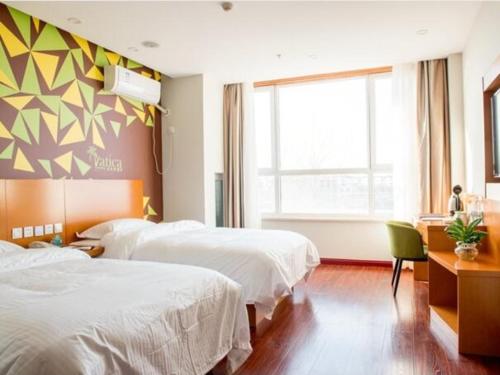 a hotel room with two beds and a window at Vatica Tianjin Wuqing District Cuihuangkou Hotel in Wuqing