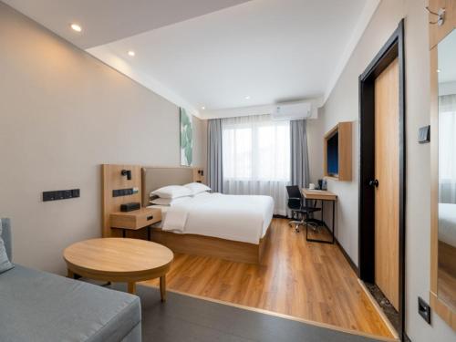 a hotel room with a bed and a desk and a table at GreenTree Inn Suzhou Railway Station Park Road Hotel in Suzhou