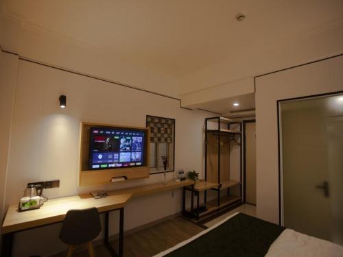 a bedroom with a desk with a television on a wall at GreenTree Inn Jiangsu Lianyungang Guannan West Renmin Road Express Hotel in Guannan