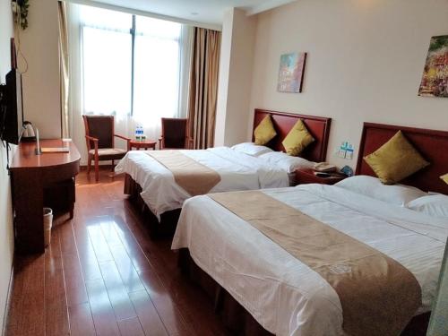 a hotel room with two beds and a desk at GreenTree Inn ShangHai South JiangYang Road South ChangJiang Road Express Hotel in Baoshan