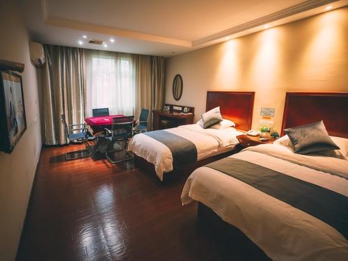 a hotel room with two beds and a desk at GreenTree Inn Zhejiang Lishui Suichang Longgu Road Express Hotel in Suichang