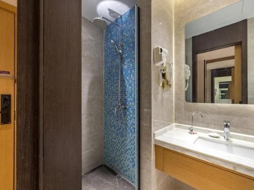 ein Bad mit einer Dusche, einem Waschbecken und einem Spiegel in der Unterkunft GYA Xuzhou High Speed Railway Station West Exit Station Hotel in Xuzhou