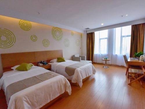 een hotelkamer met 2 bedden en een bureau bij GreenTree Inn Huanggang Qichun County Ouyada Square Express Hotel in Qichun