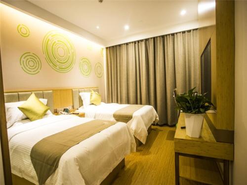 a hotel room with two beds and a potted plant at GreenTree Inn Xingtai Julu County Fengqing Road Business Hotel in Xingtai