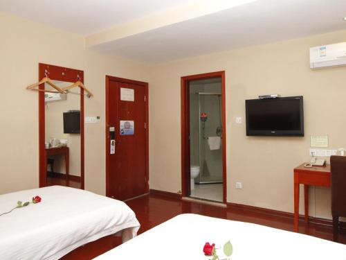 a room with two beds and a flat screen tv at GreenTree Inn Rizhao West Station Suning Plaza in Rizhao