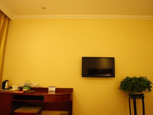 a yellow wall with a flat screen television on it at GreenTree Inn Shandong Zaozhuang Xuecheng District Road Taishan Road Road Communist Youth League School Express Hotel in Zaozhuang