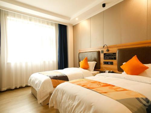 a hotel room with two beds and a window at Shell Tianshui Maiji District Erma Road Walking Street Hotel in Tianshui