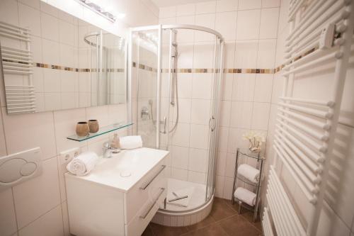 biała łazienka z prysznicem i umywalką w obiekcie Alpenzauber Whg.25 w Garmisch Partenkirchen