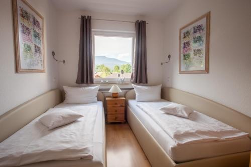 dwa łóżka w pokoju z oknem w obiekcie Alpenzauber Whg.25 w Garmisch Partenkirchen