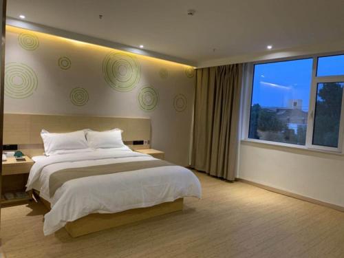a bedroom with a large bed and a large window at GreenTree Inn Dezhou Bus Station Train Station Express Hotel in Dezhou