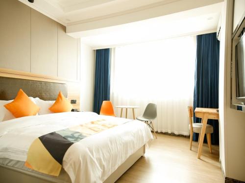 a bedroom with a bed and a desk and a window at Shell Tianshui Maiji District Erma Road Walking Street Hotel in Tianshui