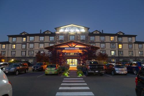 a large building with cars parked in a parking lot at Bayview Hotel in Courtenay