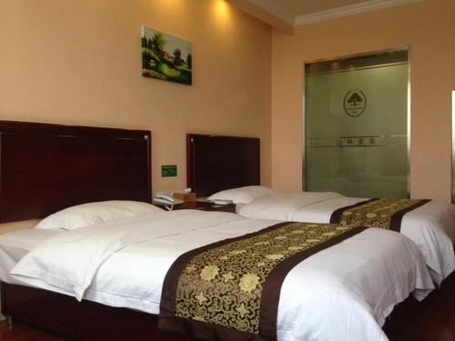two beds in a hotel room with white sheets at GreenTree Inn Jiangsu ZhenJiang Jurong New Bus Station Express Hotel in Jurong
