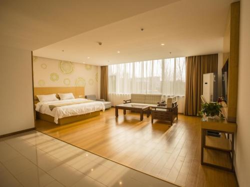 une grande chambre avec un lit et un salon dans l'établissement GreenTree Inn Handan Wei County Xianbiao Business Hotel, à Handan