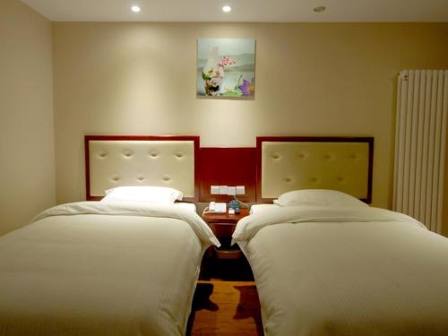 two beds in a hotel room with at GreenTree Inn ShanDong TaiAn Bus Station LingShan Street Express Hotel in Tai'an