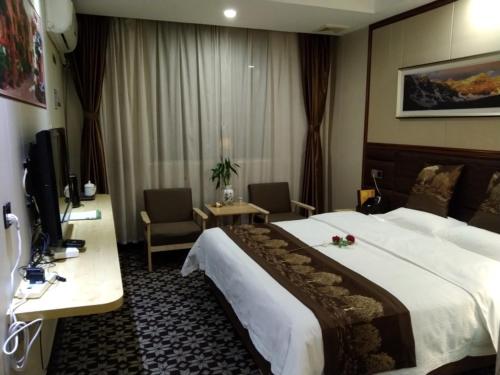 Cette chambre comprend un grand lit et un bureau. dans l'établissement GreenTree Alliance Xinyang Pingqiao District Nanjing Road Dongyang Hotel, à Xinyang