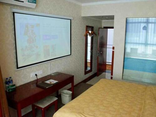 a bedroom with a bed and a desk and a projection screen at GreenTree Inn Datong West Xiangyang Street Express Hotel in Datong