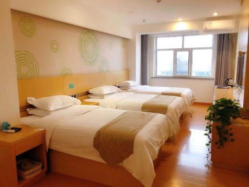 um quarto de hotel com três camas e uma janela em GreenTree Inn Wulanchabu High Speed Railway Station Huaiyuan South Road Express Hotel em Pingdiquan