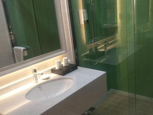 a bathroom with a sink and a glass shower at GreenTree Inn Yancheng Tinghu Area Wanda Square Hotel in Yancheng