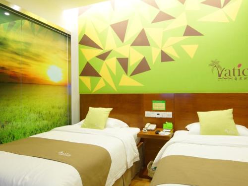 a hotel room with two beds and a wall with a painting at Vatica AnHui Fuyang Linquan South Jiefang Hotel. in Linquan