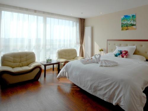 a bedroom with a large white bed and two chairs at GreenTree Inn ShanDong TaiAn Bus Station LingShan Street Express Hotel in Tai'an